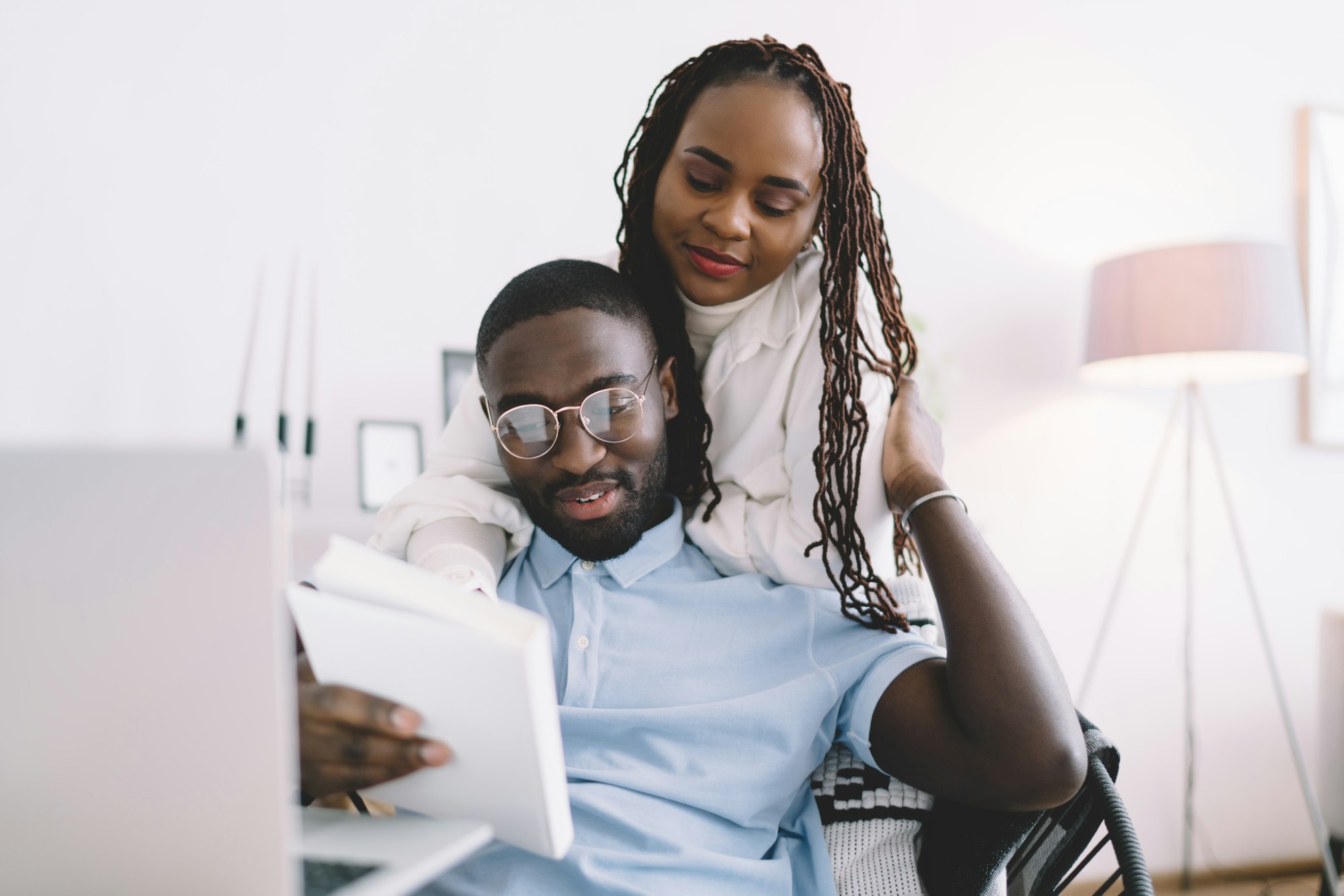 Happy black couple with book embracing at home